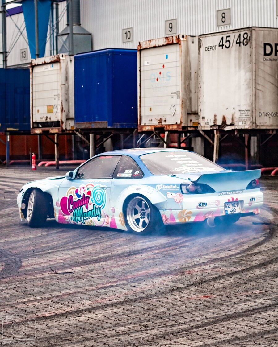 Candy-S14.9 driftet vor Containern, Reifenspuren auf dem Asphalt